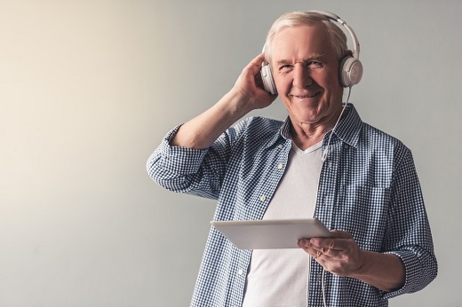 A man with headphones on holding a tablet